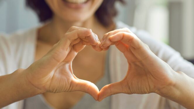 A happy customer makes a heart to signal love with their hands